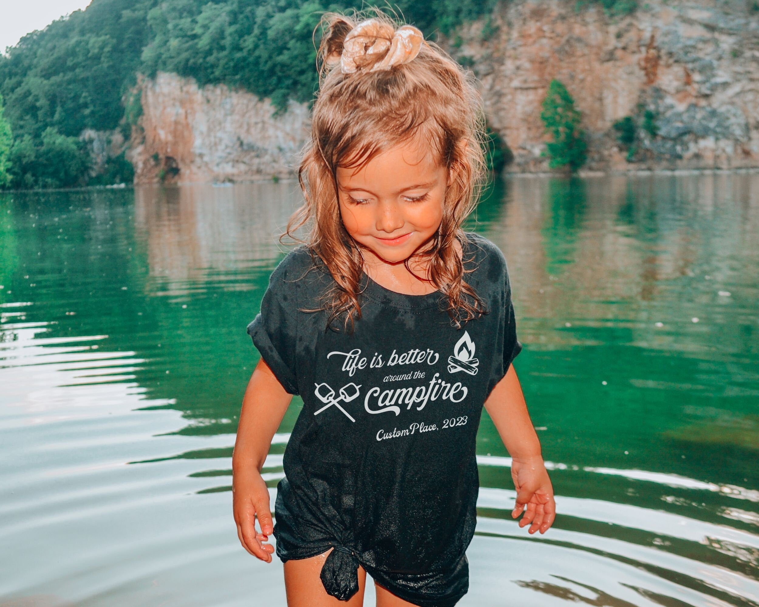 Girl wearing kids custom matching family camping shirts with life is better around the campfire design on black shirt