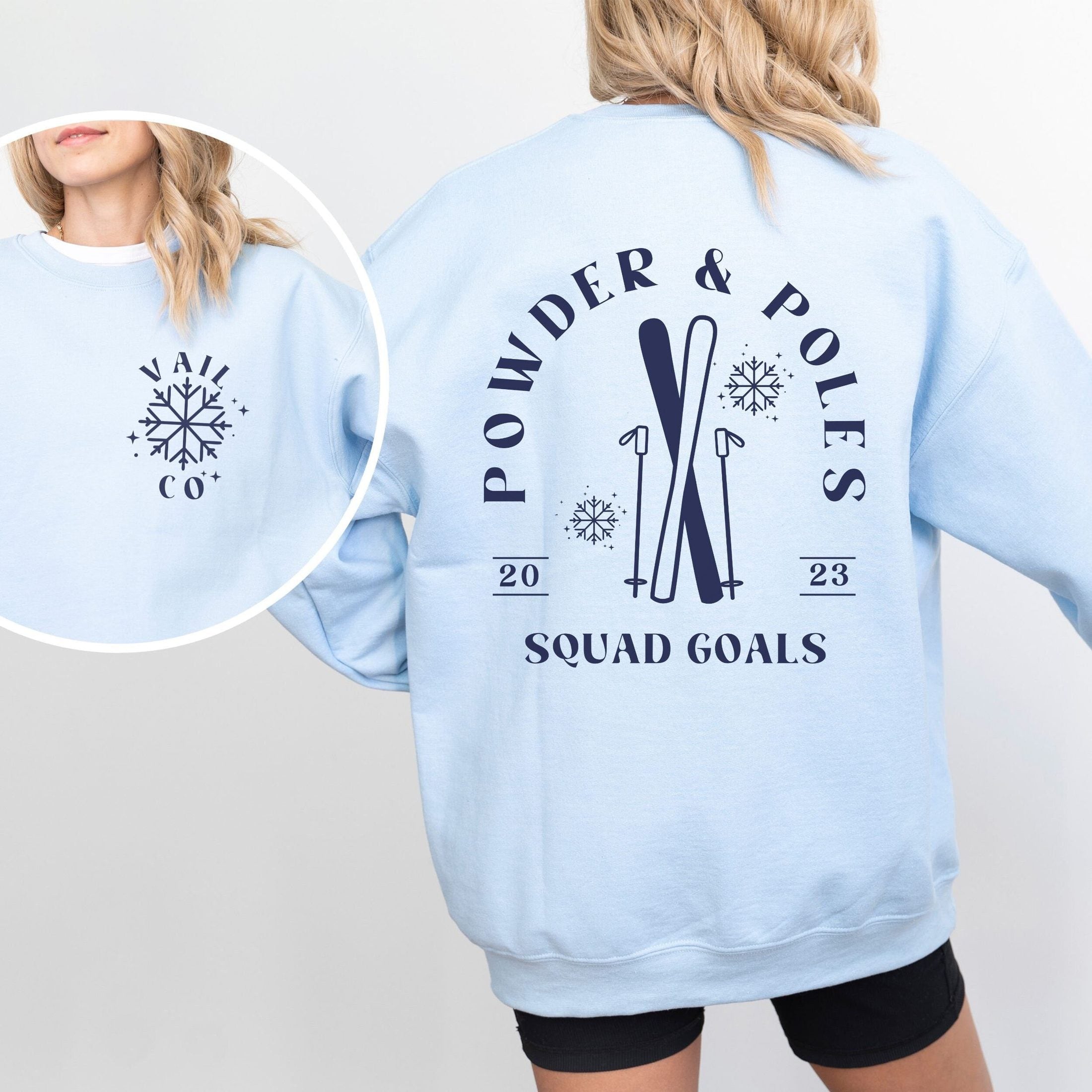 Woman wearing custom matching group girls ski trip sweatshirt with powder and poles design on light blue crewneck