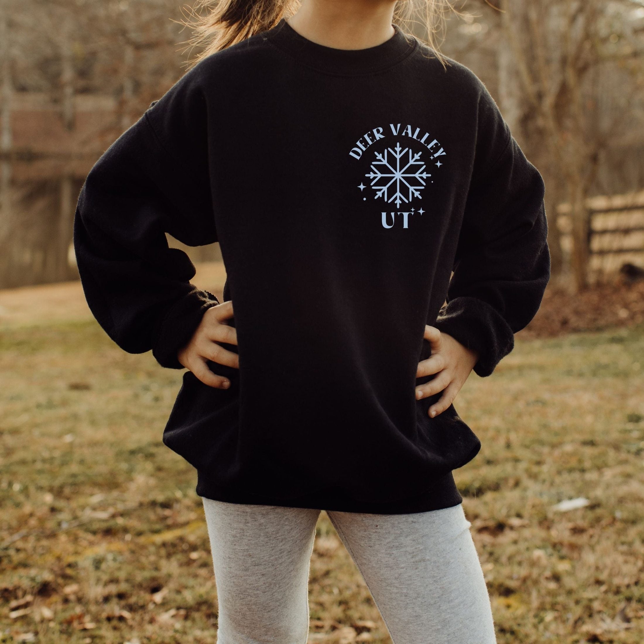 Girl wearing custom matching group girls ski trip sweatshirt with powder and poles design on black crewneck