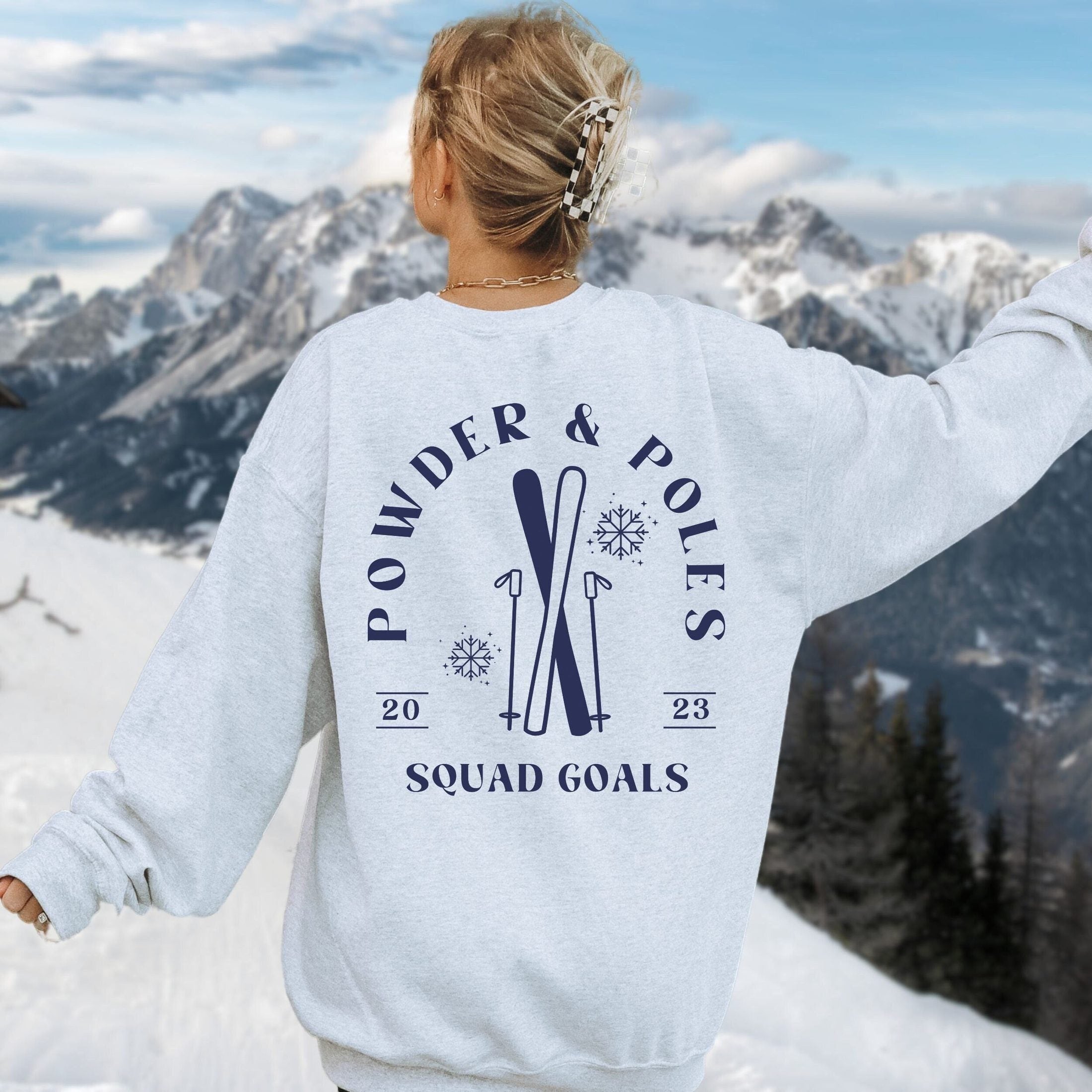 Woman wearing custom matching group girls ski trip sweatshirt with powder and poles design on ash crewneck