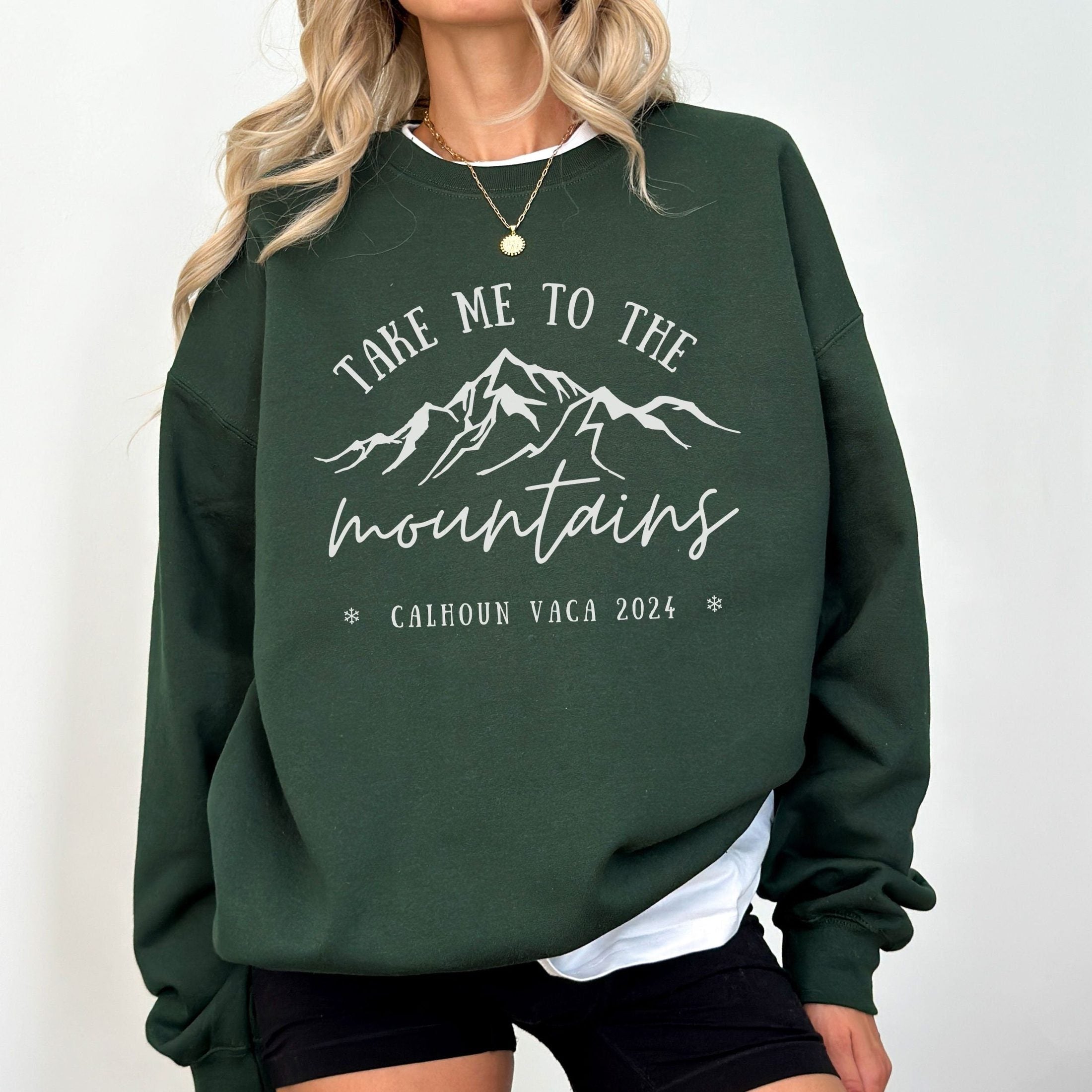 woman wearing custom matching family vacation take me to the mountains shirt for group ski weekend trips. shown in forest green crewneck sweatshirt