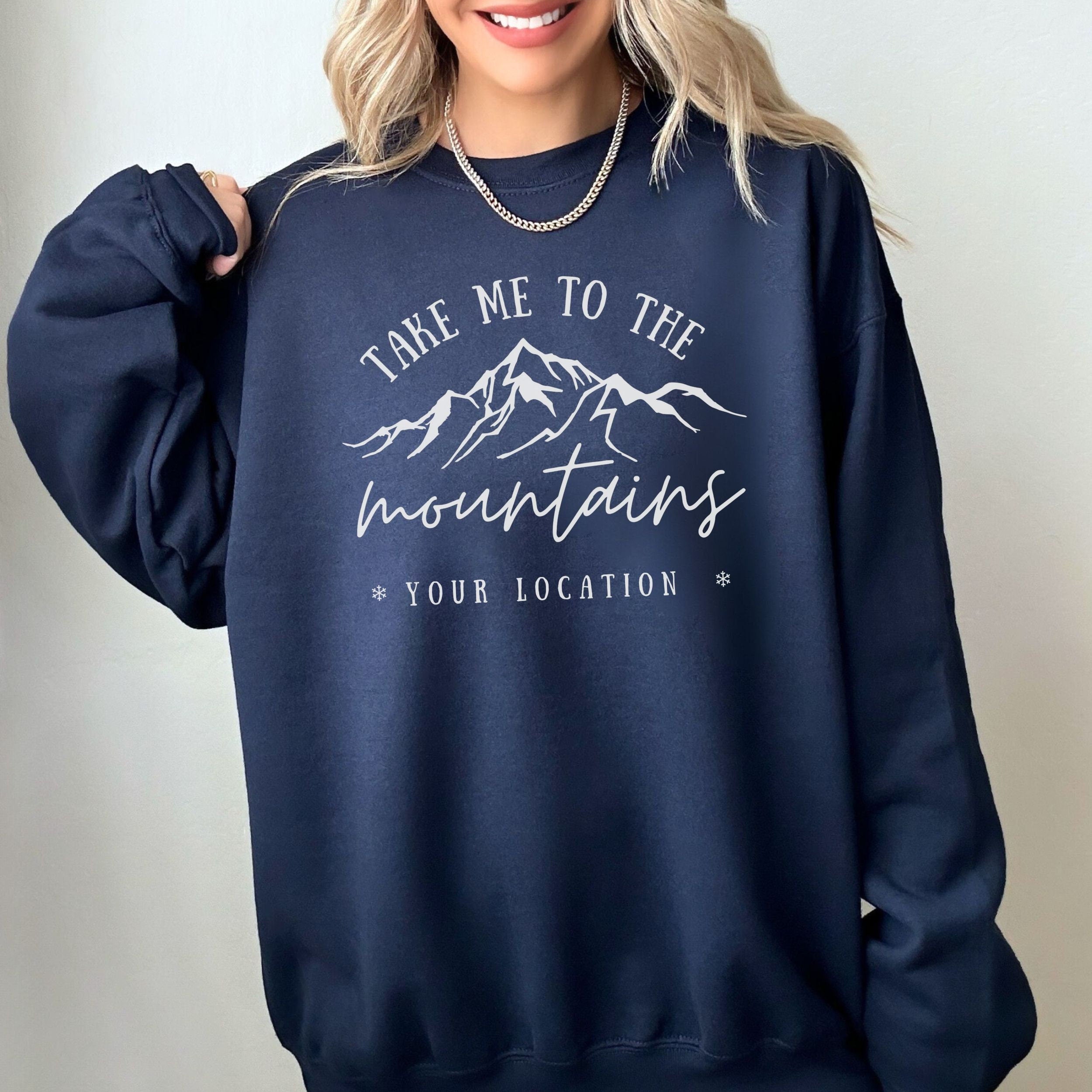 woman wearing custom matching family vacation take me to the mountains shirt for group ski weekend trips. shown in navy crewneck sweatshirt