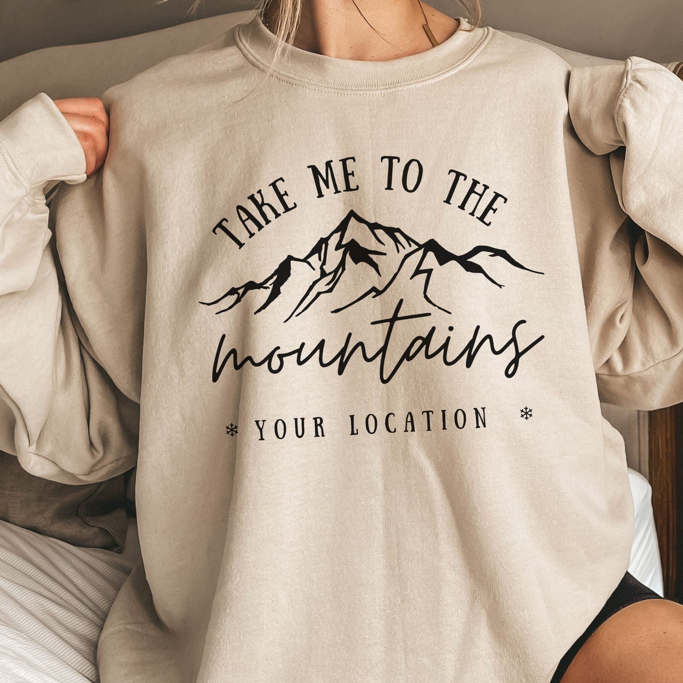 woman wearing custom matching family vacation take me to the mountains shirt for group ski weekend trips. shown in sand crewneck sweatshirt