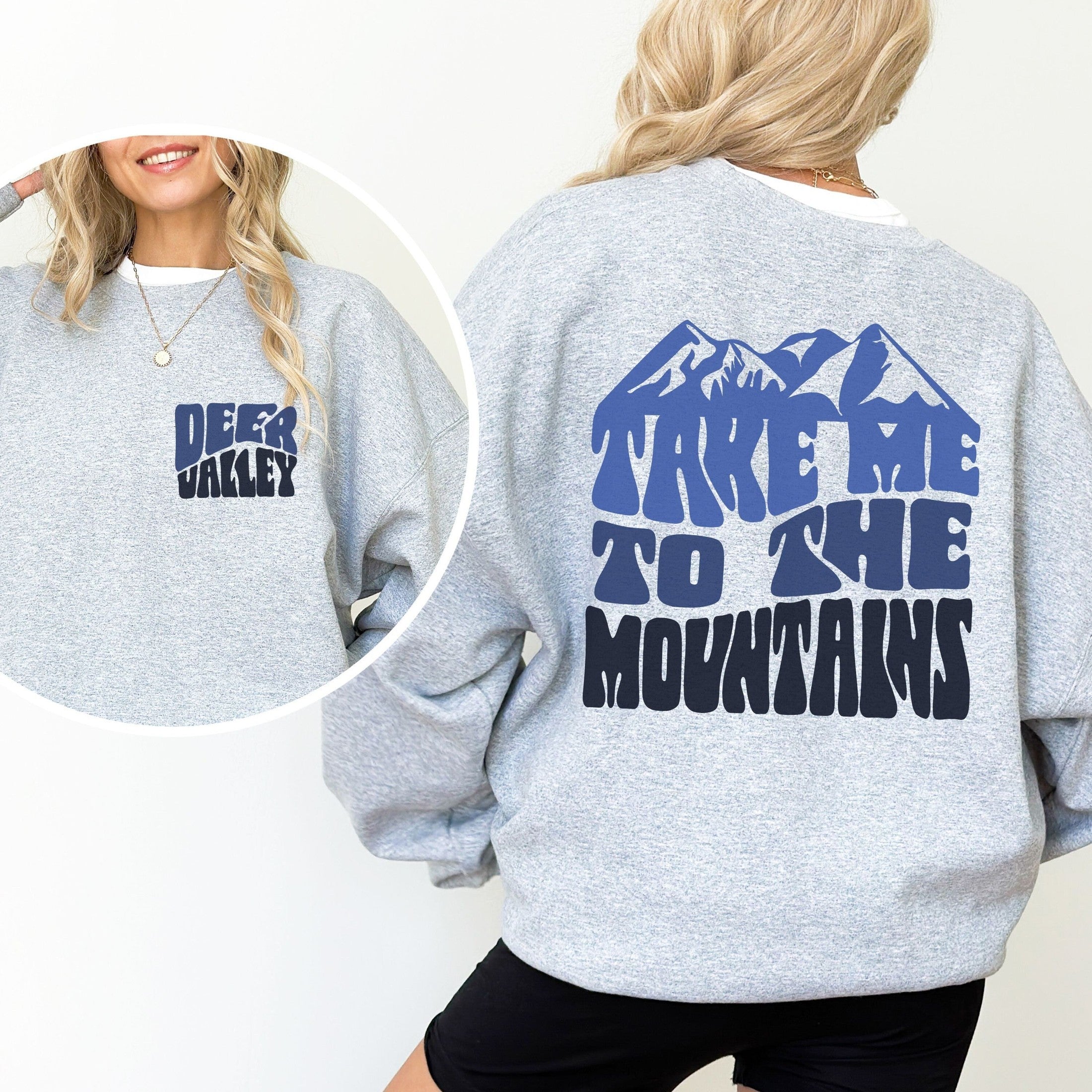 Woman wearing custom matching family adventure vacation shirt with blue retro style Take Me To The Mountains design. Perfect for group ski weekends. Shown on gray crewneck sweatshirt.