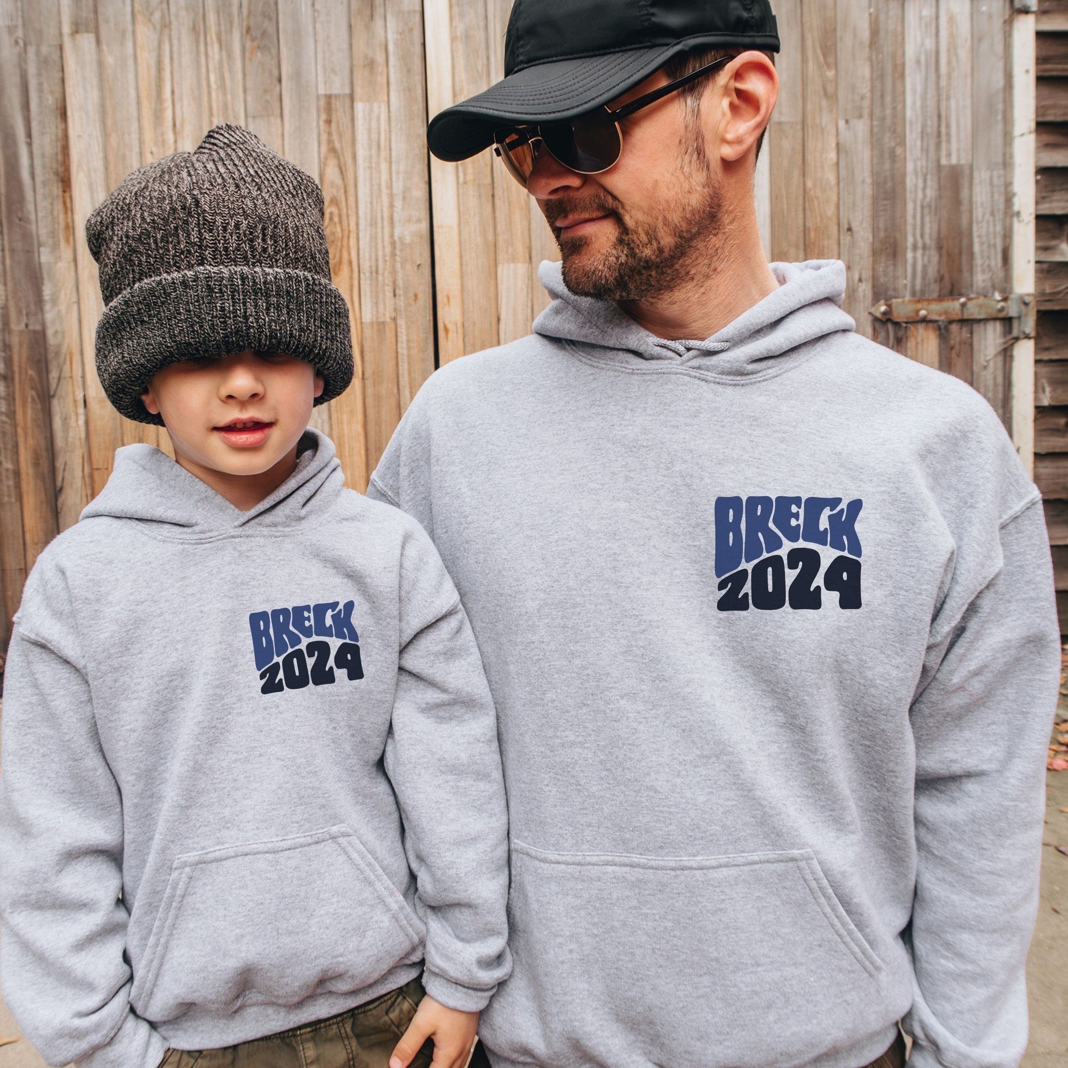man and boy wearing custom matching family adventure vacation shirt with blue retro style Take Me To The Mountains design. Perfect for group ski weekends. Shown on gray hoodie.
