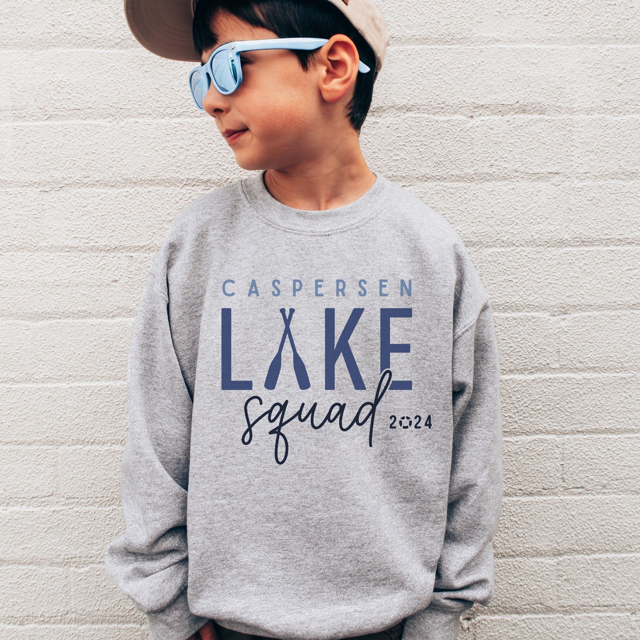 boy wearing custom matching family Lake Squad shirts personalized with name and year. Perfect for group lake vacations, shown in gray crewneck sweatshirt