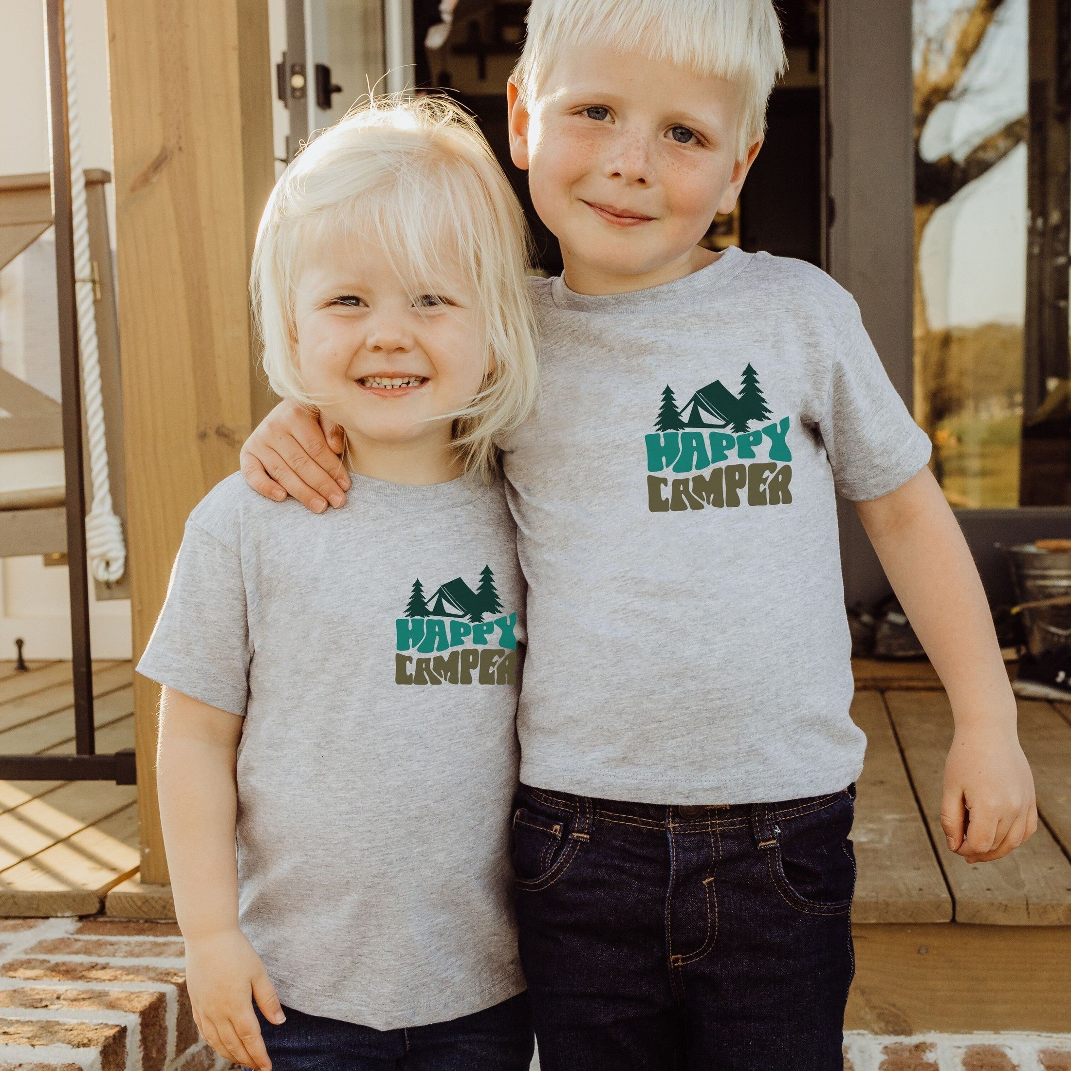 boy and girl wearing custom matching family adventure vacation shirt with green retro style Happy Camper design. Perfect for group camping trips. Shown on gray tshirt.