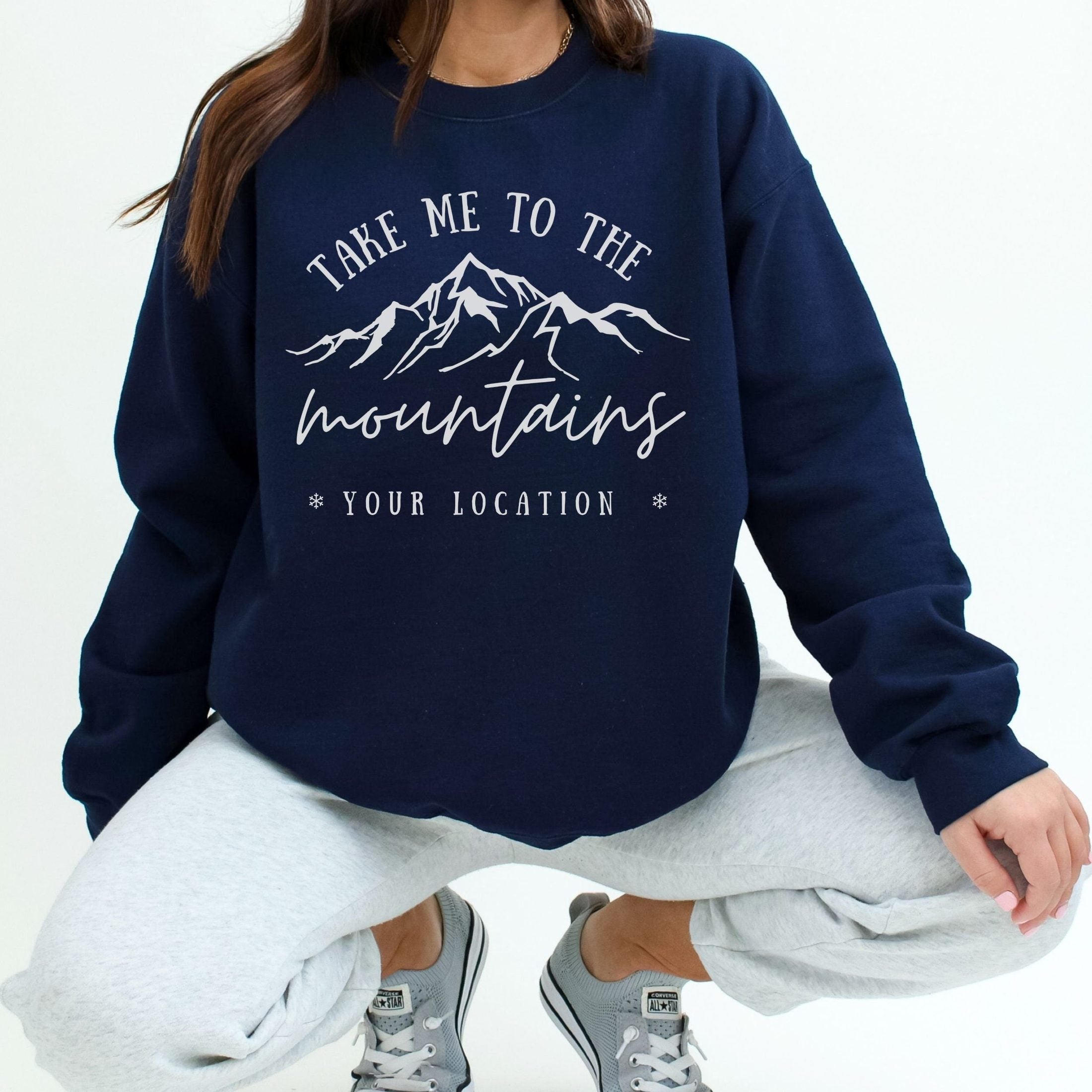 woman wearing custom matching family vacation take me to the mountains shirt for group ski weekend trips. shown in navy crewneck sweatshirt