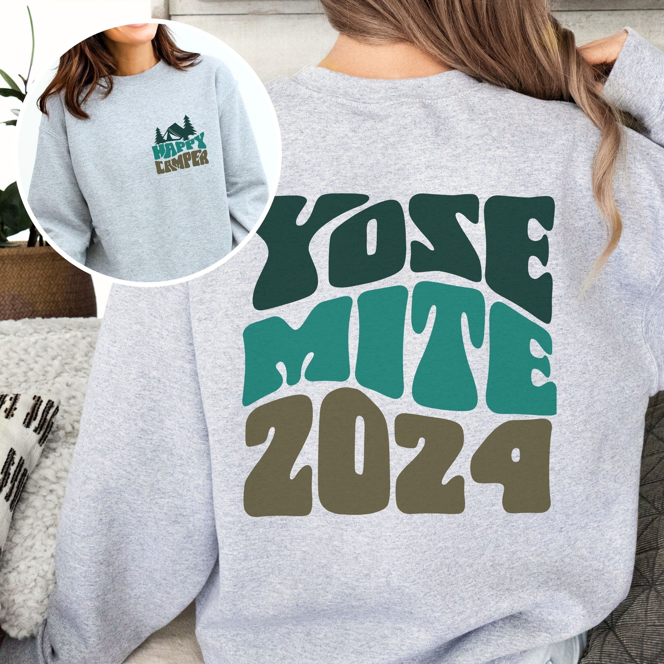 woman wearing custom matching family adventure vacation shirt with green retro style Happy Camper design. Perfect for group camping trips. Shown on gray crewneck sweatshirt.