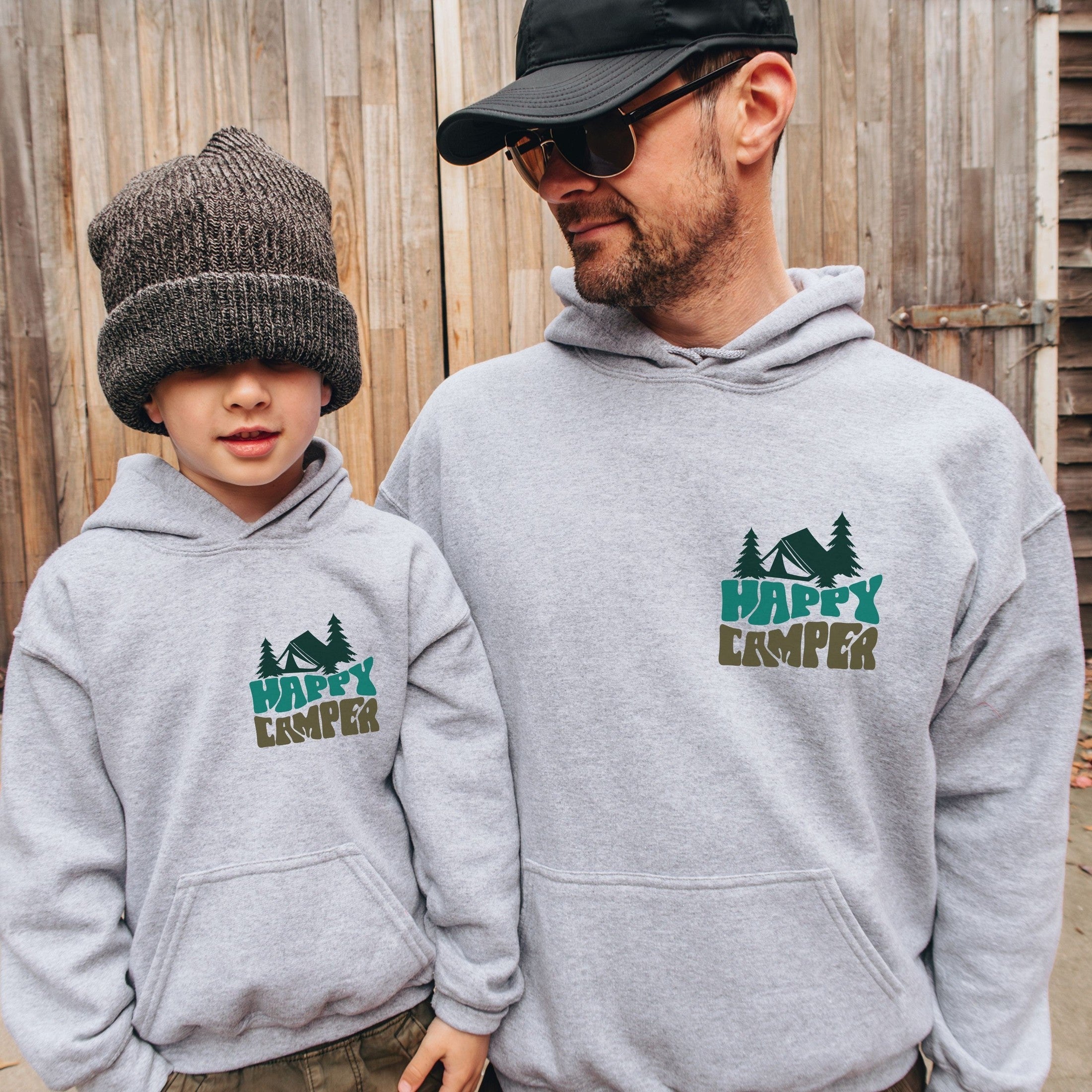 man and boy wearing custom matching family adventure vacation shirt with green retro style Happy Camper design. Perfect for group camping trips. Shown on gray hoodies