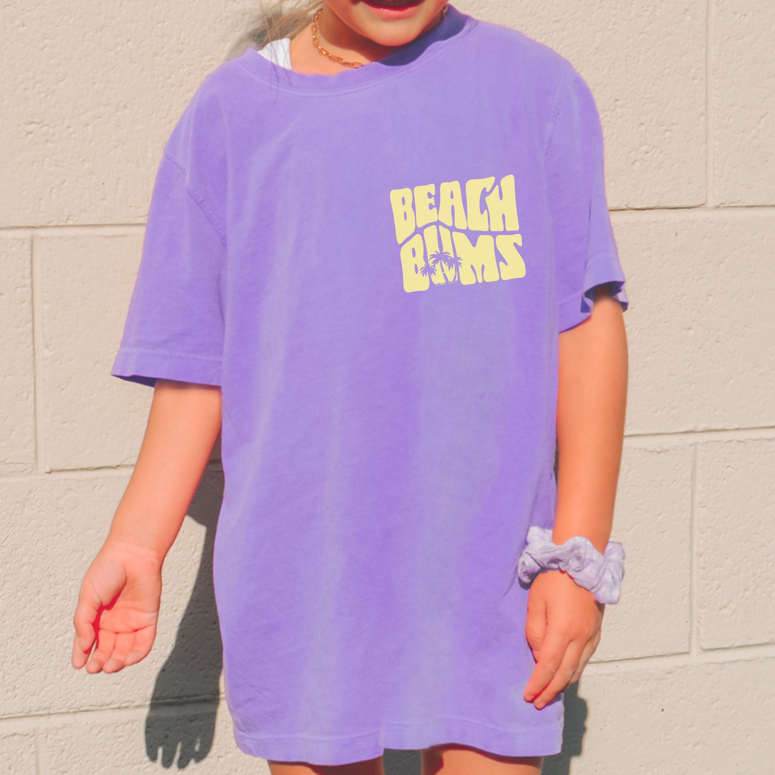 Woman wearing matching family vacation shirt with retro beach bums design in comfort colors violet