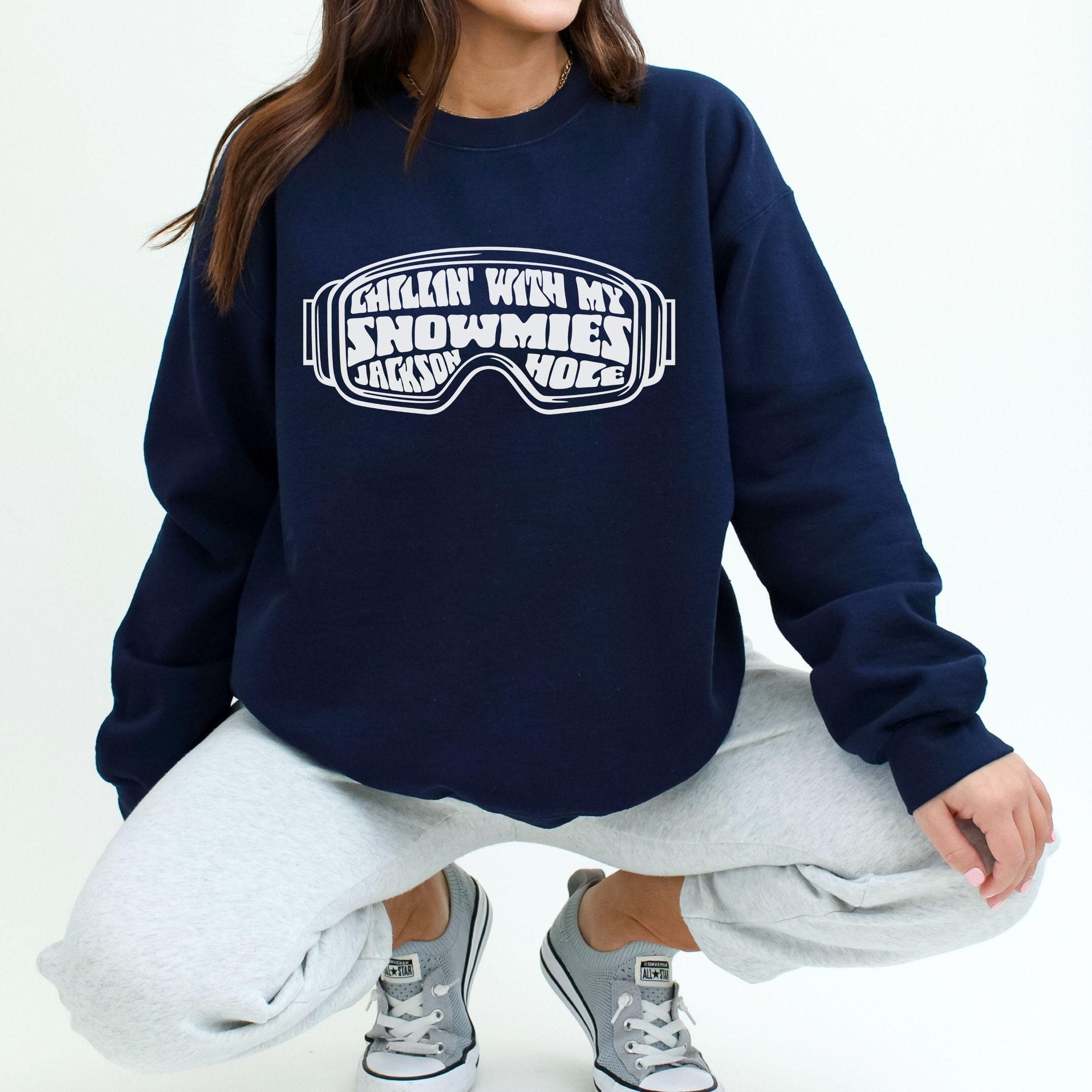 woman wearing custom matching family winter vacation shirts with funny Chillin With My Snowmies goggles design perfect for group ski trip weekends shown on black crewneck sweatshirt