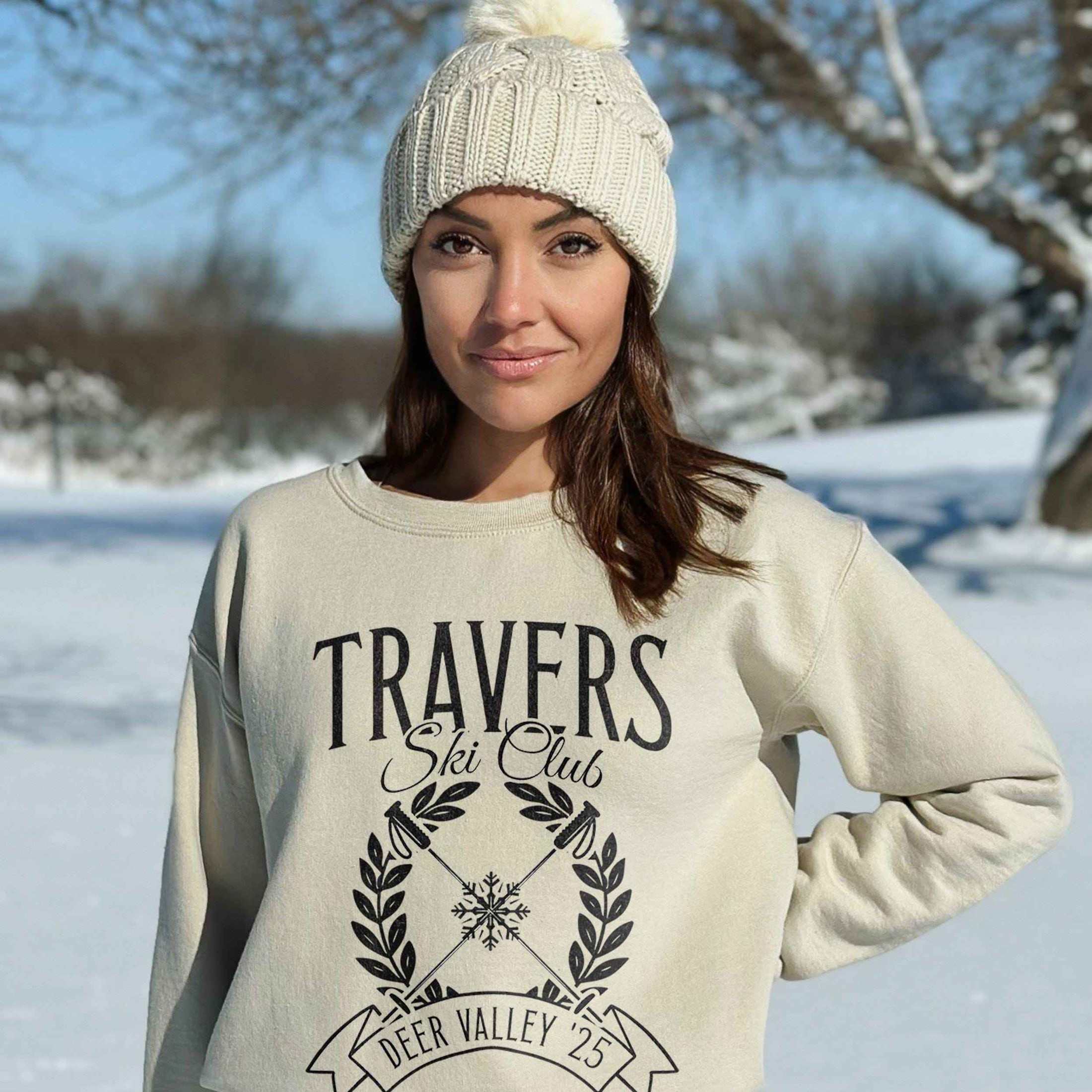 woman wearing custom matching family vacation preppy ski club logo shirt for group ski weekend trips. shown in sand crewneck sweatshirt