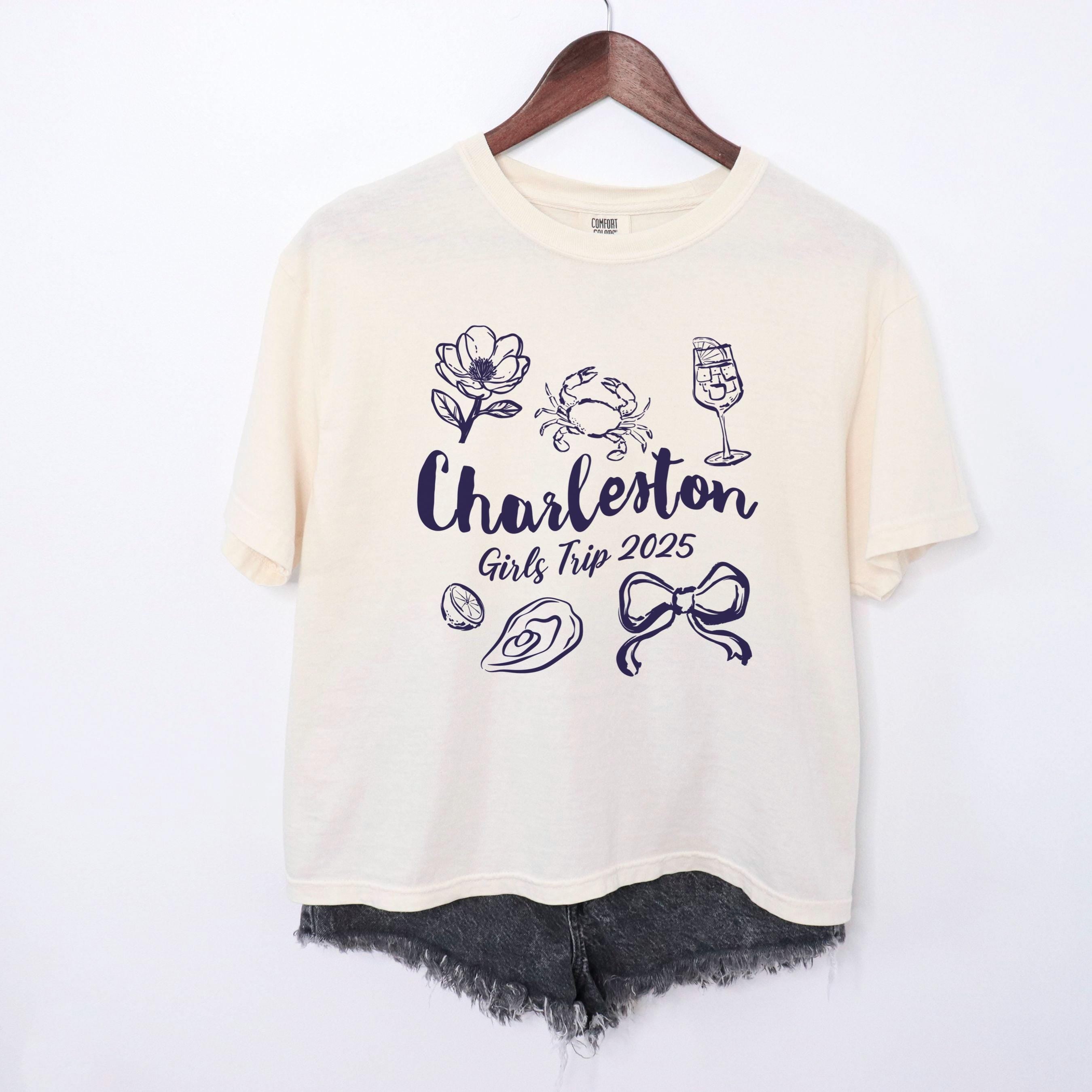 Charleston girls trip shirt with coquette bow and travel doodle design, printed on Comfort Colors Ivory boxy crop tee for matching group vacations
