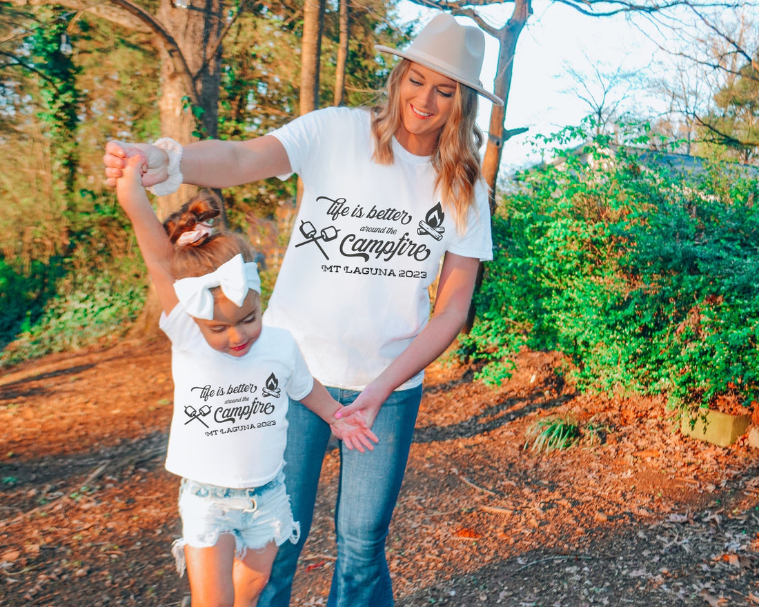 Mother and daughter wearing Custom matching family camping shirts with life is better around the campfire design on white shirts