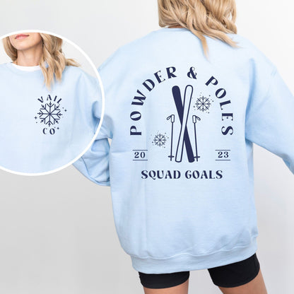Woman wearing custom matching group girls ski trip sweatshirt with powder and poles design on light blue crewneck