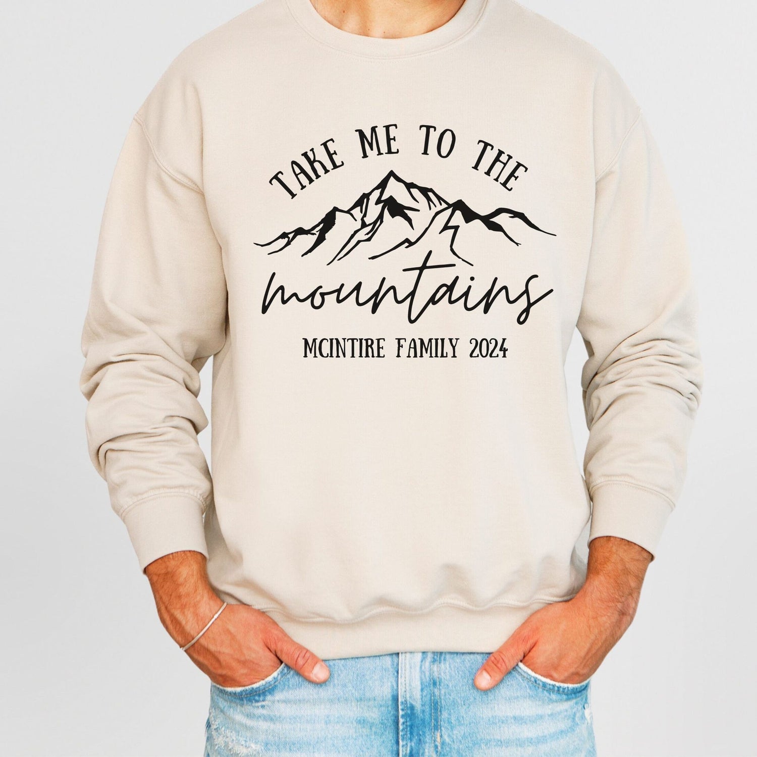 man wearing custom matching family vacation take me to the mountains shirt for group ski weekend trips. shown in sand crewneck sweatshirt