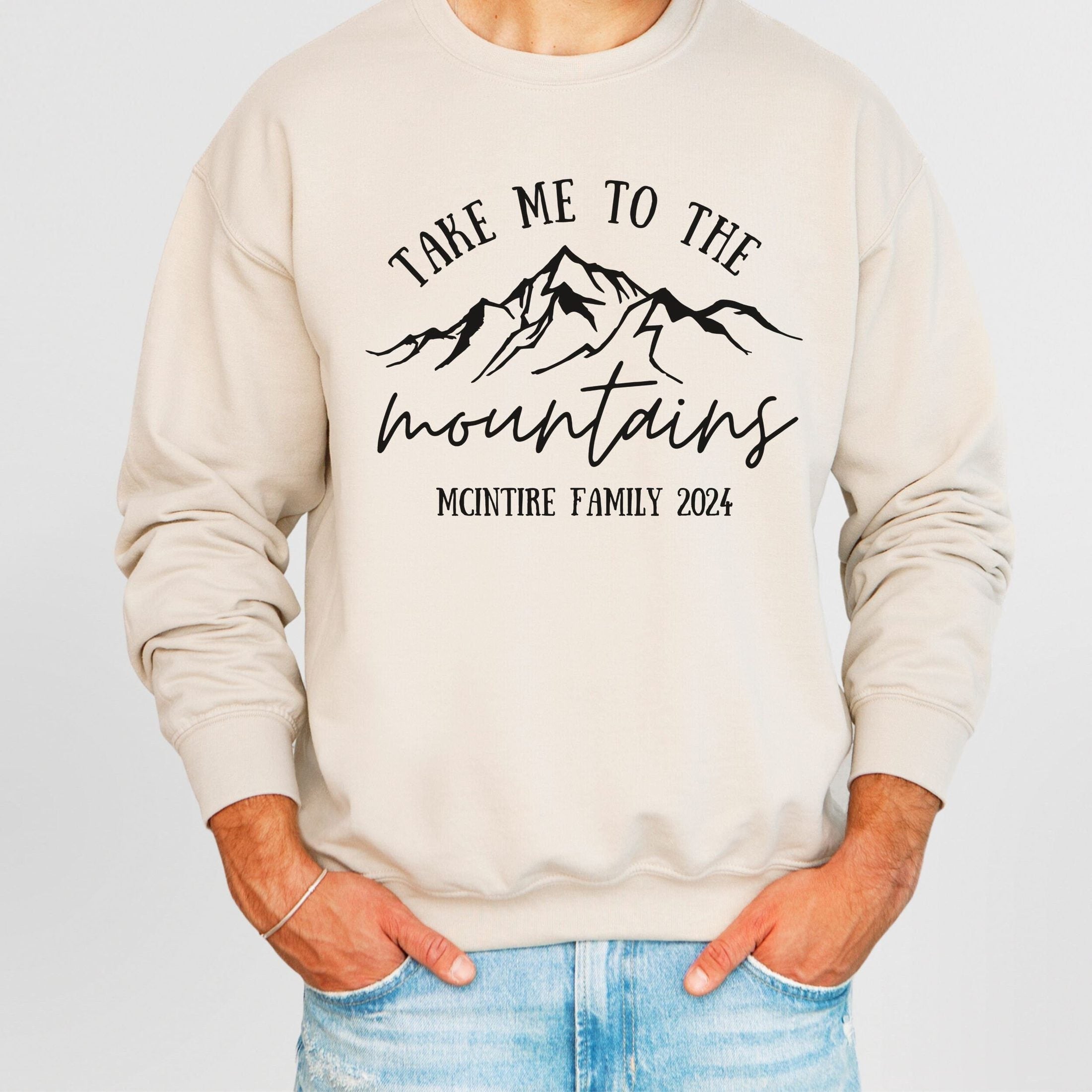 man wearing custom matching family vacation take me to the mountains shirt for group ski weekend trips. shown in sand crewneck sweatshirt