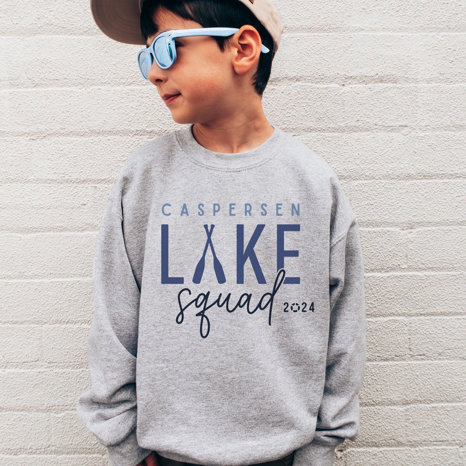 boy wearing custom matching family Lake Squad shirts personalized with name and year. Perfect for group lake vacations, shown in gray crewneck sweatshirt