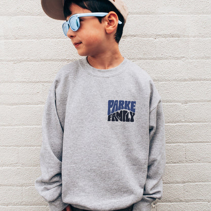 boy wearing custom matching family adventure vacation shirt with blue retro style Take Me To The Mountains design. Perfect for group ski weekends. Shown on gray crewneck sweatshirt.