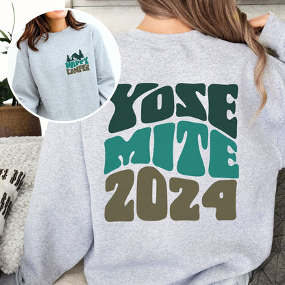 woman wearing custom matching family adventure vacation shirt with green retro style Happy Camper design. Perfect for group camping trips. Shown on gray crewneck sweatshirt.