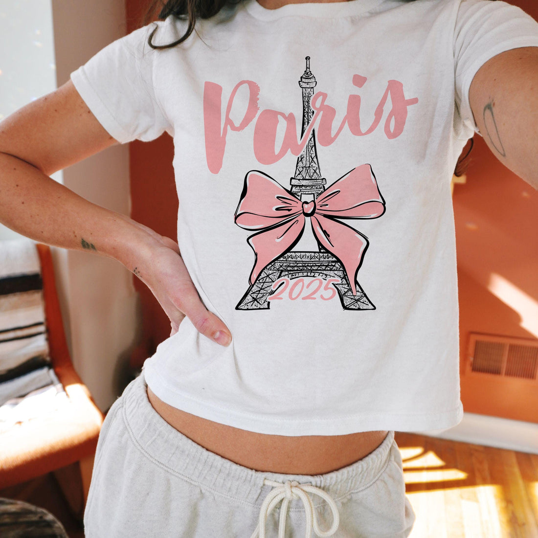 Custom Paris 2025 coquette-style t-shirt with Eiffel Tower and bow graphic, great for matching girls trip outfits